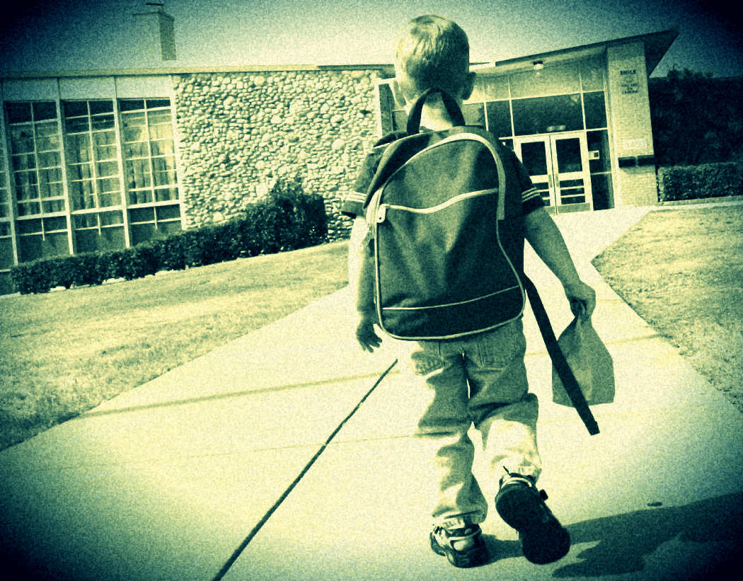 a picture of a young boy, shot from behind, showing him on his first day of school